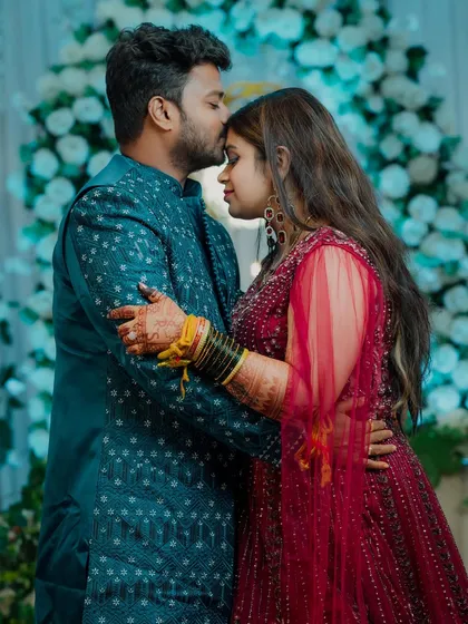 A quiet, romantic moment during the reception. The groom kisses his bride's forehead as they hold each other close, a perfect candid shot that captures their love.