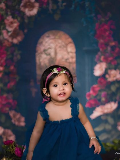 A little love bug in a magical garden. This beautiful portrait with a floral backdrop captures the sweet and curious nature of a toddler.