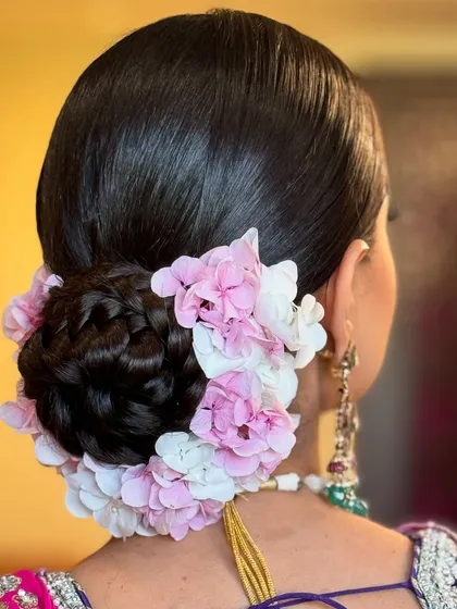 A closer look at a classic floral bun created for a Sikh bride's Anand Karaj ceremony. The neat, braided bun is encircled with beautiful pink and white hydrangeas, offering a soft and elegant frame for the bride's look.