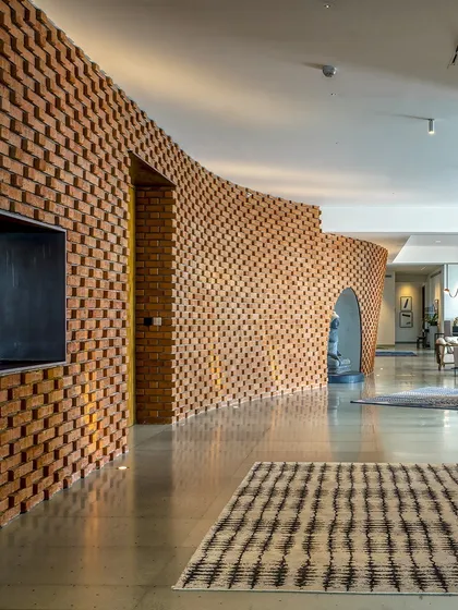 In the Sampurna Residence, we used a curving brick wall to create an 'animated streetscape' within the home. This element guides movement and defines space, transforming a simple corridor into an artistic and experiential journey.