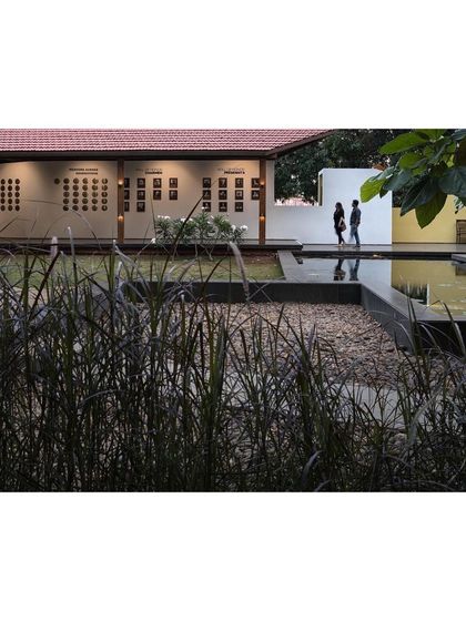 A view across the pebble court and lotus pond towards the museum's exhibition wall. The landscape design creates multiple layers and vantage points.