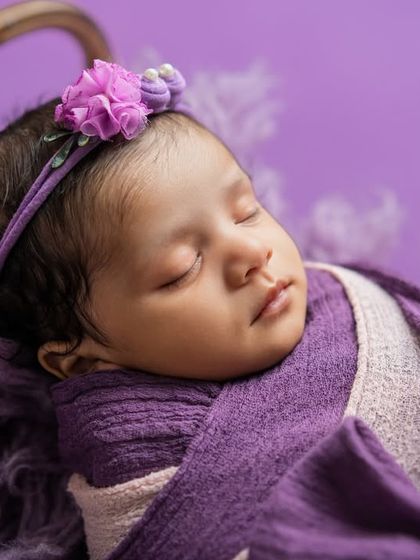 A close-up on this sleeping beauty, showing the soft texture of the purple wrap and the delicate floral headband. These details make each photo special.