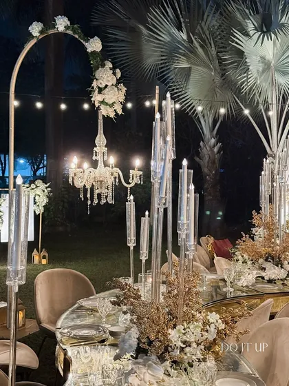 An elegant anniversary dinner setup. The mirrored table reflects the glow of crystal candelabras and a delicate chandelier, creating a sophisticated and romantic ambiance for a special celebration.