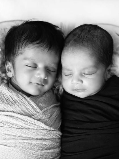 A beautiful black and white portrait of newborn twins sleeping side-by-side, each wrapped in their own swaddle. Double the love!