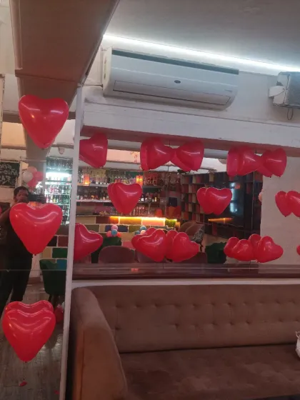 Simple romantic touches in a cafe, with red heart-shaped foil balloons hanging from the ceiling.