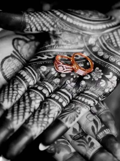 We believe the details tell a story. This close-up shot focuses on the wedding rings resting on the bride's intricate mehndi, symbolizing the union of love and tradition in a single, artistic frame.