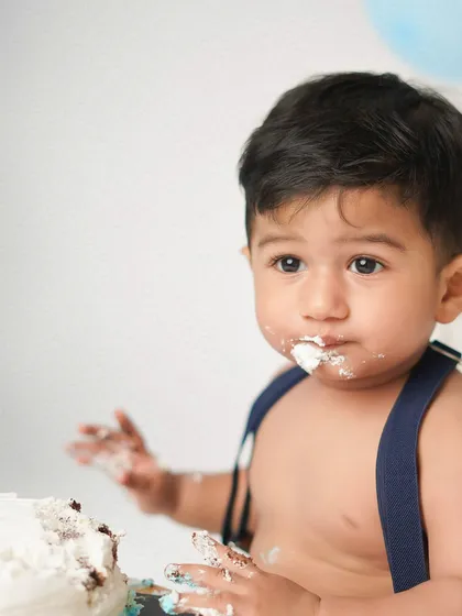 A close-up of the birthday boy with frosting on his face. This is the signature shot of any successful cake smash session.