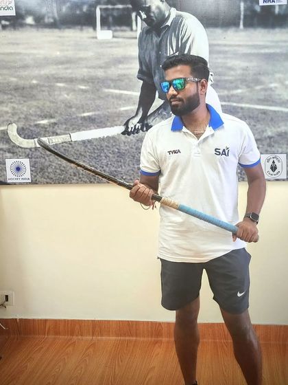 Holding a piece of history. Posing with a vintage hockey stick in front of a photo of a legend. It's a reminder of the rich heritage of our sport.