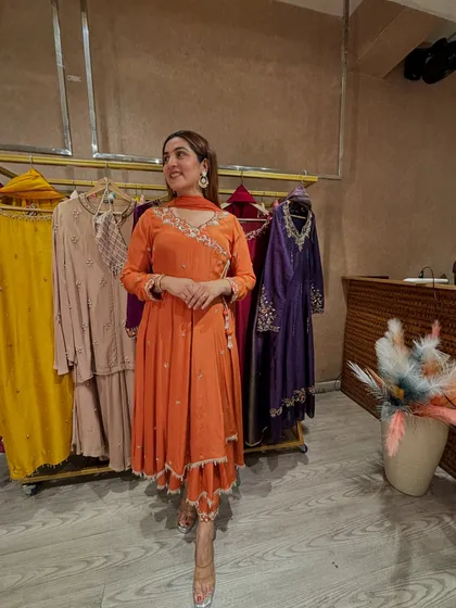 A full view of the orange angrakha suit, showcasing its beautiful flare and tassel details. It is a complete look that is festive, elegant, and perfect for making a statement.