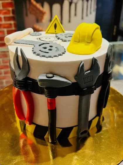 A civil engineering-themed cake decorated with fondant tools like a hammer, pliers, and a hard hat.