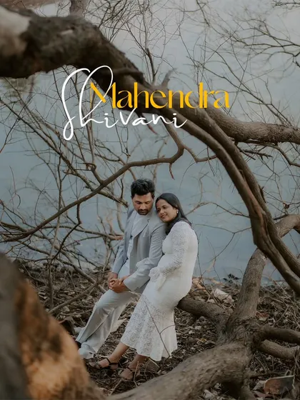 A romantic portrait of a couple sitting on a fallen tree by the water, framed by the natural environment for an intimate and earthy feel.