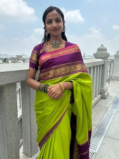 A client looking graceful in a lime green and purple pure Mysore crepe saree at a temple.