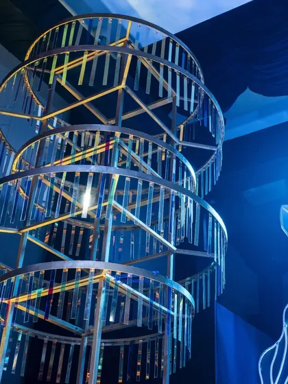 A close-up of a multi-tiered, rotating chandelier structure. This custom-built piece, made with iridescent panels, served as a kinetic sculpture and a major focal point of the Sangeet decor.