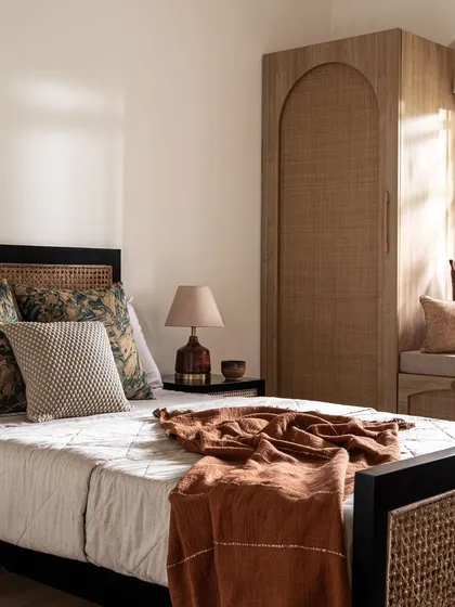This angle highlights the warmth of the rattan wardrobe and headboard, paired with a black bed frame for a touch of modern contrast. This design is ideal for creating a timeless, resort-like feel.