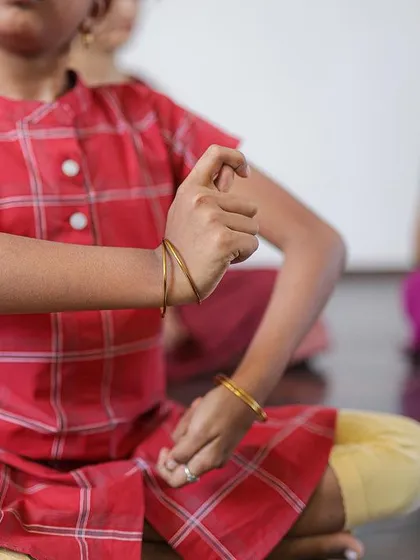 A close-up of a young student's hand gesture, or mudra. We start with the basics, ensuring a strong foundation in the language of Bharatanatyam from the very beginning.