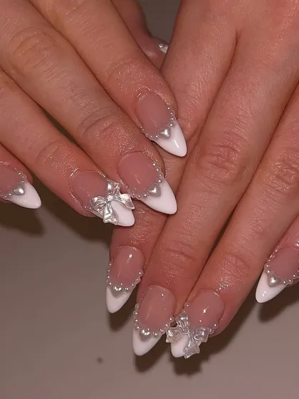A modern take on bridal nails, these feature a classic French tip base on stiletto extensions. We added 3D pearl hearts and delicate silver bows to create a look that is both romantic and incredibly chic.