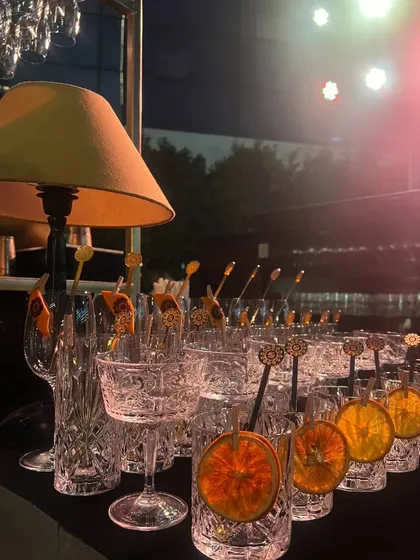 Crystal glassware and dehydrated orange slices ready for service at an elegant, warmly lit evening event.