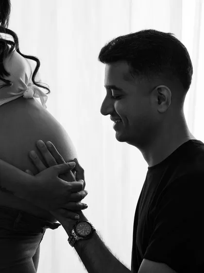 A close-up of a father-to-be admiring the baby bump. This tender moment, captured in black and white, is a memory to hold onto forever.