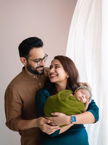 A happy family portrait with their newborn. The natural light from the window creates a soft and beautiful glow.