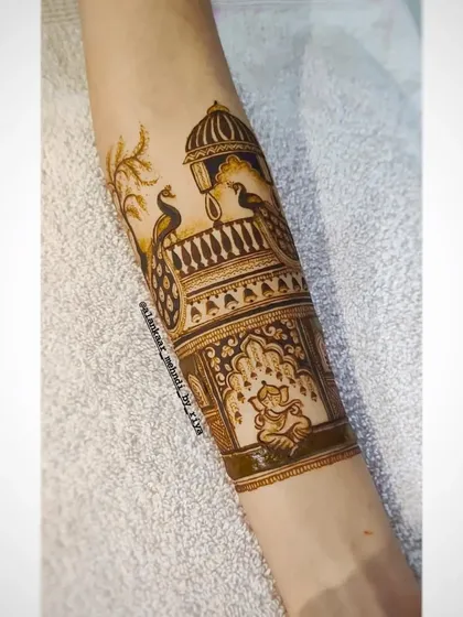 A bridal startup design for the arm, featuring peacocks on a balcony with a Ganesha motif below.