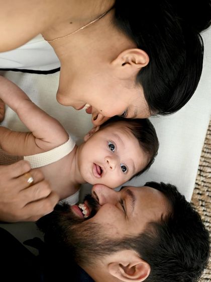 An incredibly sweet and intimate close-up. This photo captures the joyful expressions of the parents as they lie next to their curious newborn, creating a memory full of love and connection.