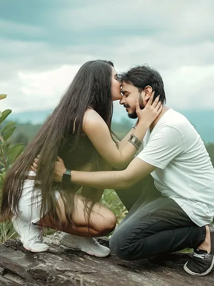 A tender forehead kiss on a scenic hilltop. This photo from a destination pre-wedding shoot in the mountains focuses on the emotional connection and intimacy between the couple, set against a stunning natural landscape.