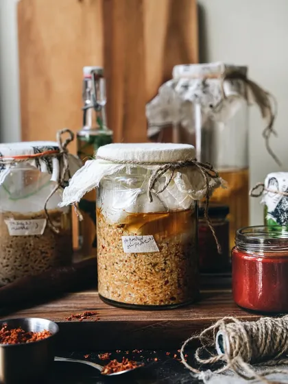 The art of visual storytelling. This image showcases homemade fermented sauces and pastes in glass jars, styled with a rustic, cozy feel to highlight the beauty of handcrafted goods.