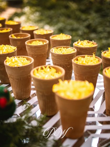 The details of a tropical Haldi. Terracotta glasses, or 'kulhads', filled with flower petals for guests to shower the couple, adding a rustic and interactive element.
