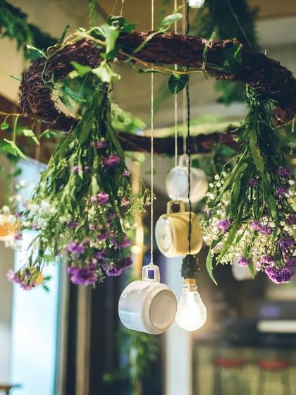 A hanging installation created for the brunch. We suspended a rustic wreath adorned with fresh flowers, trailing greenery, and charming teacups to draw the eye upward and make the space feel truly enchanted.