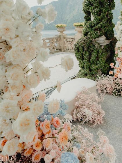 A close-up of the floral arrangements at the Lake Como wedding, with a mix of pastel hues and a touch of tangerine, all set against the breathtaking view of the lake.
