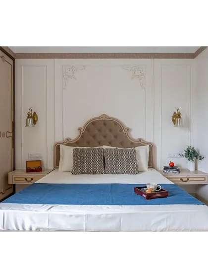 This straight-on shot highlights the symmetry of the design, with matching bedside tables and wall sconces framing the ornate bed.