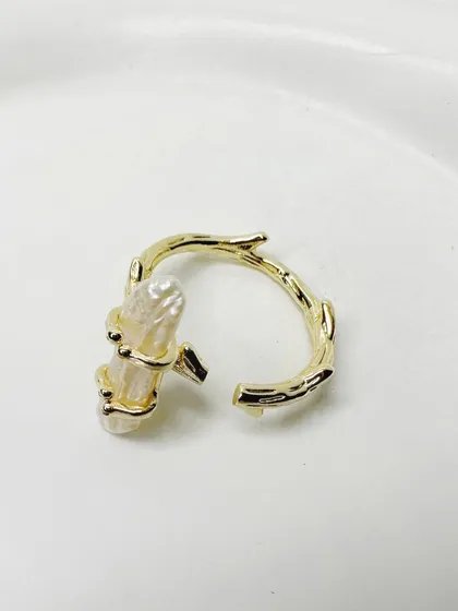 This minimal ring features a raw pearl set on a branch-like gold-plated band, inspired by nature.