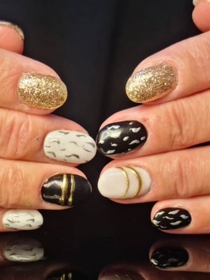 A full view of the chic black, white, and gold glitter manicure, showing the different patterns on each nail.