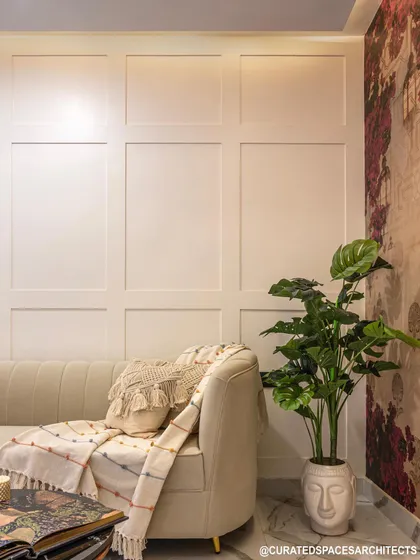 I love using wall paneling to add texture and elegance. Here, the simple white paneling provides a clean backdrop for the cozy sofa and a touch of greenery.