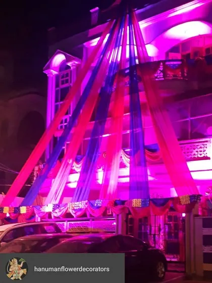 Another example of night-time exterior lighting for a celebration. This house is decorated with pink and blue drapes, which are brought to life with matching colored lights, creating a vibrant welcome for evening guests.