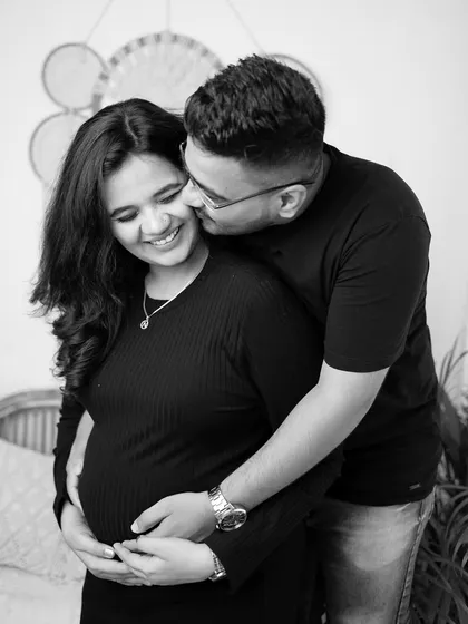 A sweet, candid moment captured in black and white. The husband-to-be whispers something to his wife, bringing out a natural, happy smile.