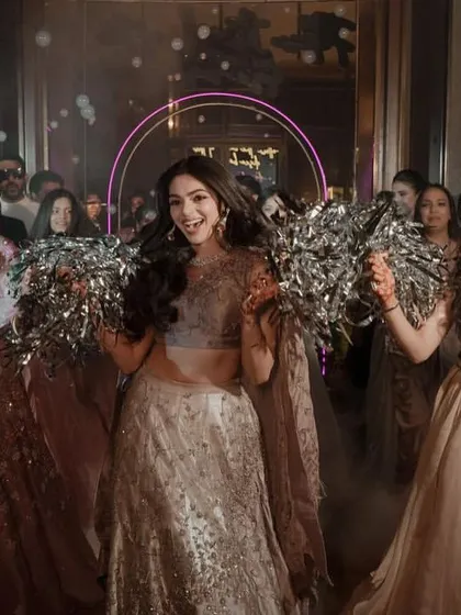 A bride's grand entry with her bridesmaids holding pom-poms, creating a celebratory and fun-filled atmosphere.