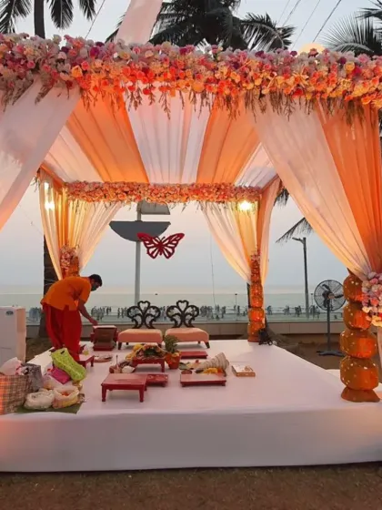As evening approaches, the lighting transforms the wedding mandap. Here, warm uplighting highlights the orange drapes and floral arrangements, creating a cozy and intimate atmosphere for the ceremony.
