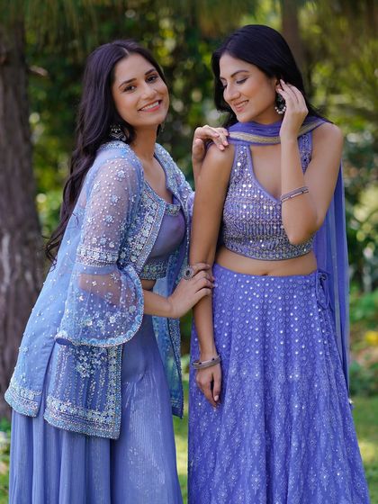 This shot captures a moment of connection between the models. It highlights the delicate embroidery on the jackets and blouses while creating a warm, friendly atmosphere for the brand.