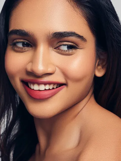 Radiant skin and a happy smile. This portrait showcases a healthy, glowing complexion paired with a beautiful red-pink lip. It's a perfect example of fresh and modern beauty.