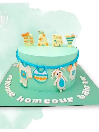 A welcome cake for a baby boy, decorated with a clothesline of baby items and a cute bunny.