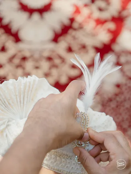 A close-up detail shot of the groom's safa being prepared, highlighting the intricate details of his wedding attire.