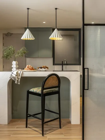 We transformed a once-dimly lit kitchen into a bright, functional heart of the home. Muted sage green cabinetry brings freshness, while the custom-curved island serves as a central gathering spot, seamlessly connecting to the dining area through pocket doors with fabric-sandwiched glass.