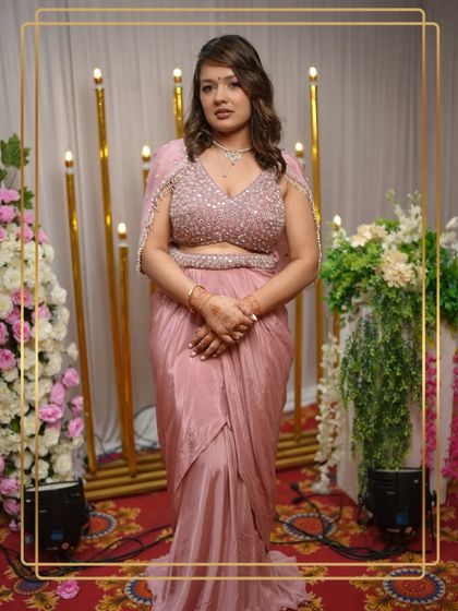 Our client looks absolutely stunning in this modern pink draped saree gown. The embellished blouse and cape-style sleeves add a touch of high-fashion glamour.