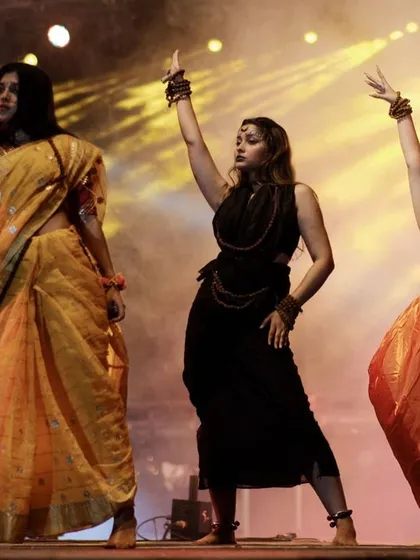 Three student performers in a coordinated pose on stage. The lighting and their expressions showcase the dedication and talent present at college events.