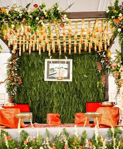 A sustainable wedding mandap in Coorg, featuring a lush green wall and vibrant, locally sourced flowers. The design reflects the couple's eco-conscious values.