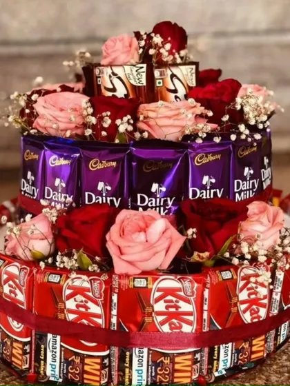 For the ultimate chocolate lover, we created this two-tier floral tower. The base is constructed with KitKat bars and the top with Dairy Milk chocolates, all adorned with fresh pink and red roses and baby's breath.