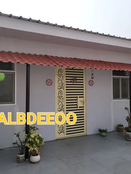 A simple and practical prefabricated house on a terrace in Indirapuram. The extended metal roof creates a nice shaded porch area, decorated with potted plants.