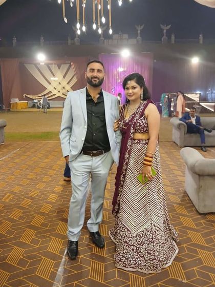 A happy couple at a wedding. The lady is wearing a beautiful wine-colored embroidered lehenga from my collection.