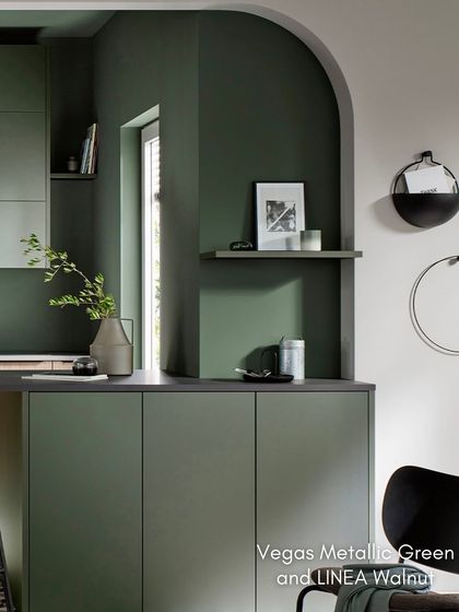 An arched entryway frames this view of the kitchen, highlighting the beautiful combination of Vegas Metallic Green and LINEA Natural Walnut.